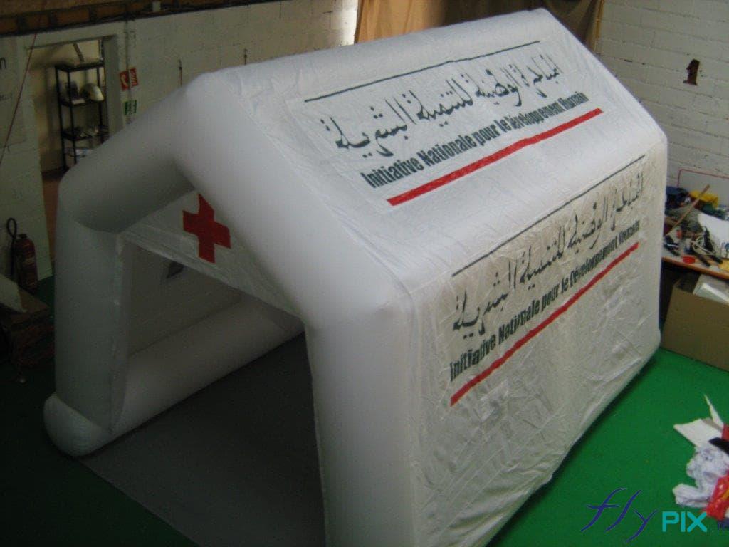 Tente de premiers secours réalisée pour le Croissant Rouge marocain. Dernièrement, nous avons réalisé une tente de premiers soins pour l'Initiative nationale pour le Développement Humain, une organisation de santé implantée au Maroc, en Afrique du Nord. Il s'agit d'un abri médical de dimensions 6 x 3 m, une structure gonflable air captif, gonflée avec une pompe électrique. La tente de premiers secours est dotée de marquages personnalisés en impression numérique couleur, de grande taille, visible de loin.