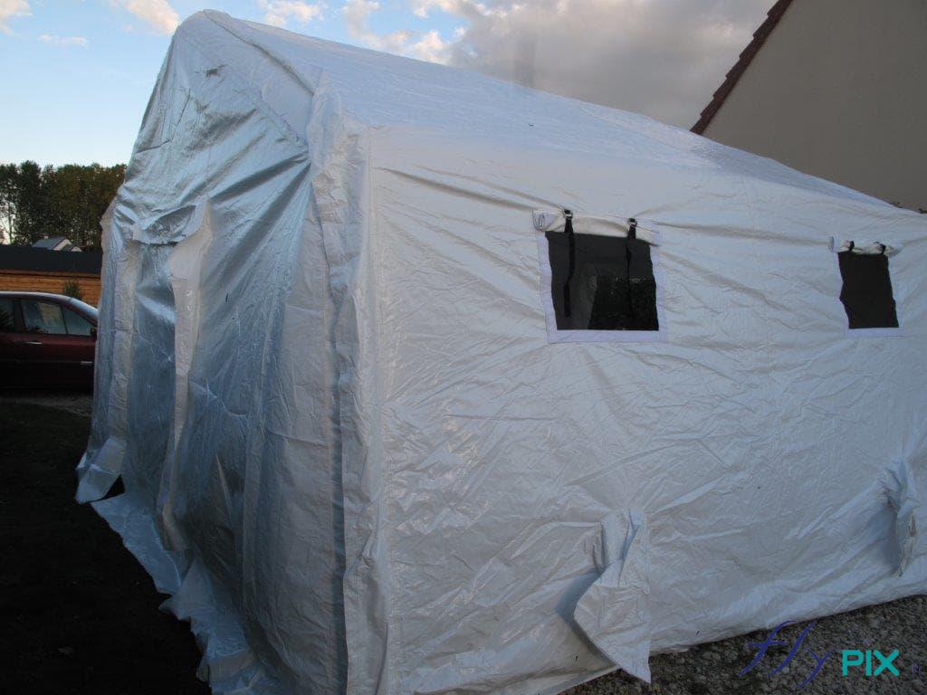 Tente médicale en forme de chapiteau, avec porte large pignon et fenêtre moustiquaire avec volets.