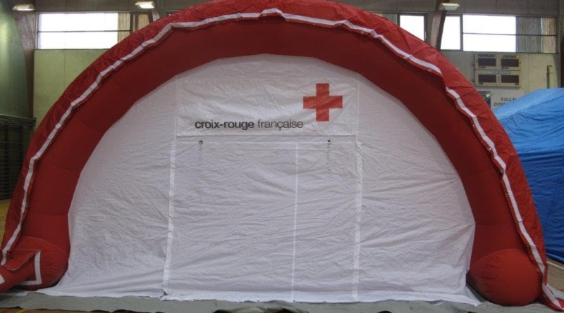 Une tente médicale gonflable en forme de demi-lune, avec le logo de la Croix Rouge Française et une porte large pigon.