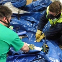 Deux techniciens sont entrain de réparer une tente médicale.