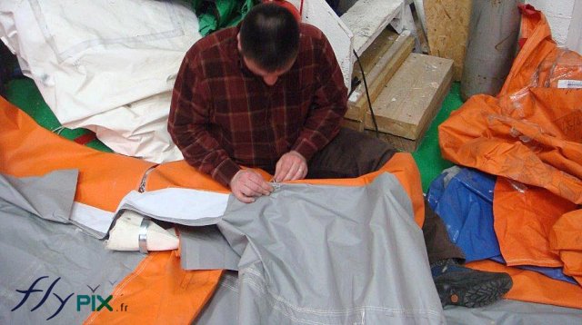 Un technicien est entrain de réparer l'enveloppe d'un mur d'une tente PMA Un technicien est entrain de réparer l'enveloppe d'un mur d'une tente PMA