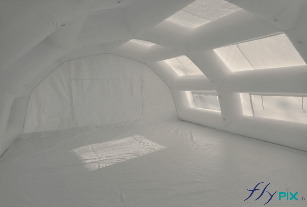 Vue intérieure de la tente PMA (Poste Médical Avancé): l’ensemble est très lumineux grâce à l’enveloppe blanche en PVC 0,6 mm. Il y a une bâche au sol lavable en PVC qui assure l’hygiène et la protection vis à vis des saletés et de la poussière en provenance du sol. De larges fenêtres, dotées de moustiquaires et de volets, permettent d’éclairer l’intérieur avec une lumière naturelle issue du soleil. Des conditions idéales pour le personnel soignant.