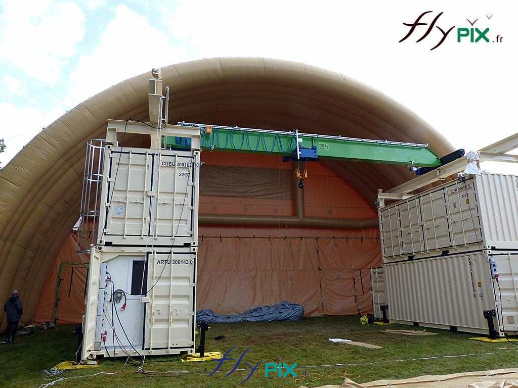 NEXTER : un module de hangar gonflable militaire de grande taille, avec une structure de grue et de containers pour la manoeuvre, placés à l'intérieur de l'abri gonflable.